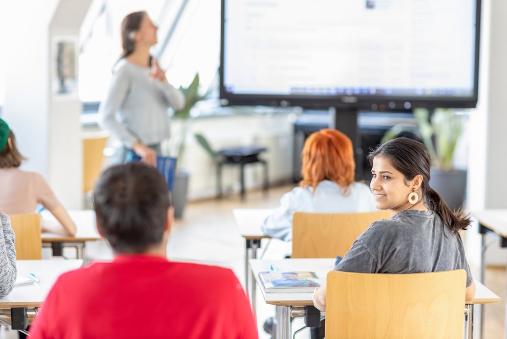 Erwachsene unterschiedlicher Herkunft sitzen in einem Klassenraum zum Deutschsprachkurs