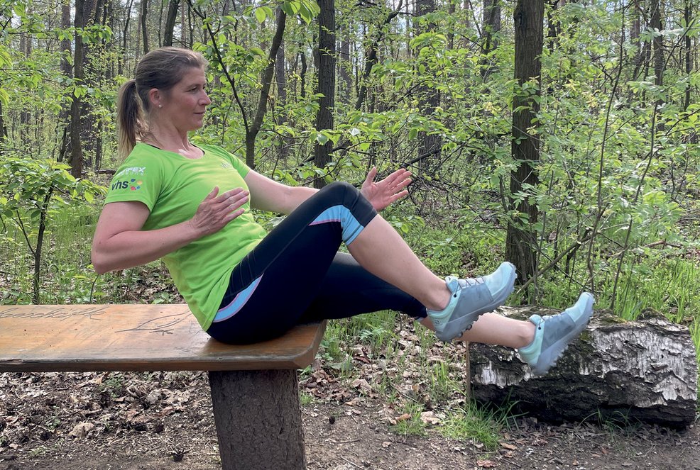 Sitzender Sprinter, Frau sitzt auf Parkbank und zieht das rechte Bein zu sich