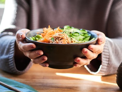Frau hält eine Reisbowl in den Händen