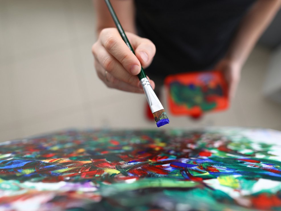 Mensch malt mit Pinsel auf Leinwand