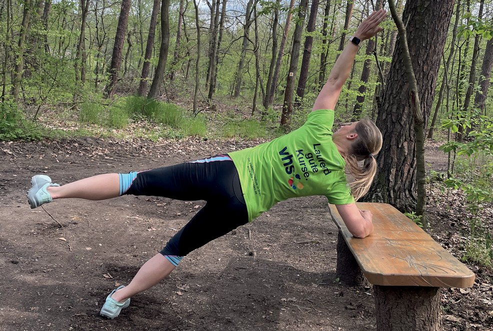 Liegendes X, Frau hat ein ausgestreckte Arm auf der Parkbank und streckt ihr Bein zur Seite
