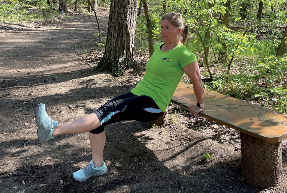 Dips Training, Frau befindet sich in der Ausgangsposition mit ausgestreckten Armen und angehobenen Beinen