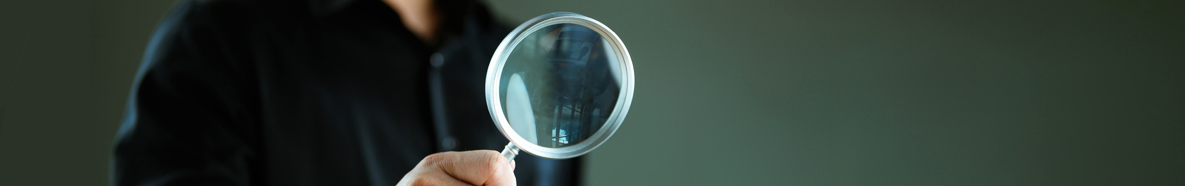 Person hält eine Lupe in der Hand
